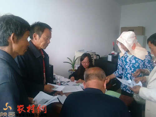 靖边县黄蒿界镇民政站一名工作人员办公桌前围满了领取救济款的农民。